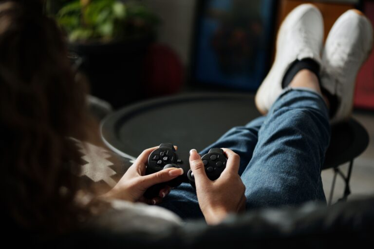 Close-up of woman gaming with a controller, feet propped up, enjoying leisure time indoors.